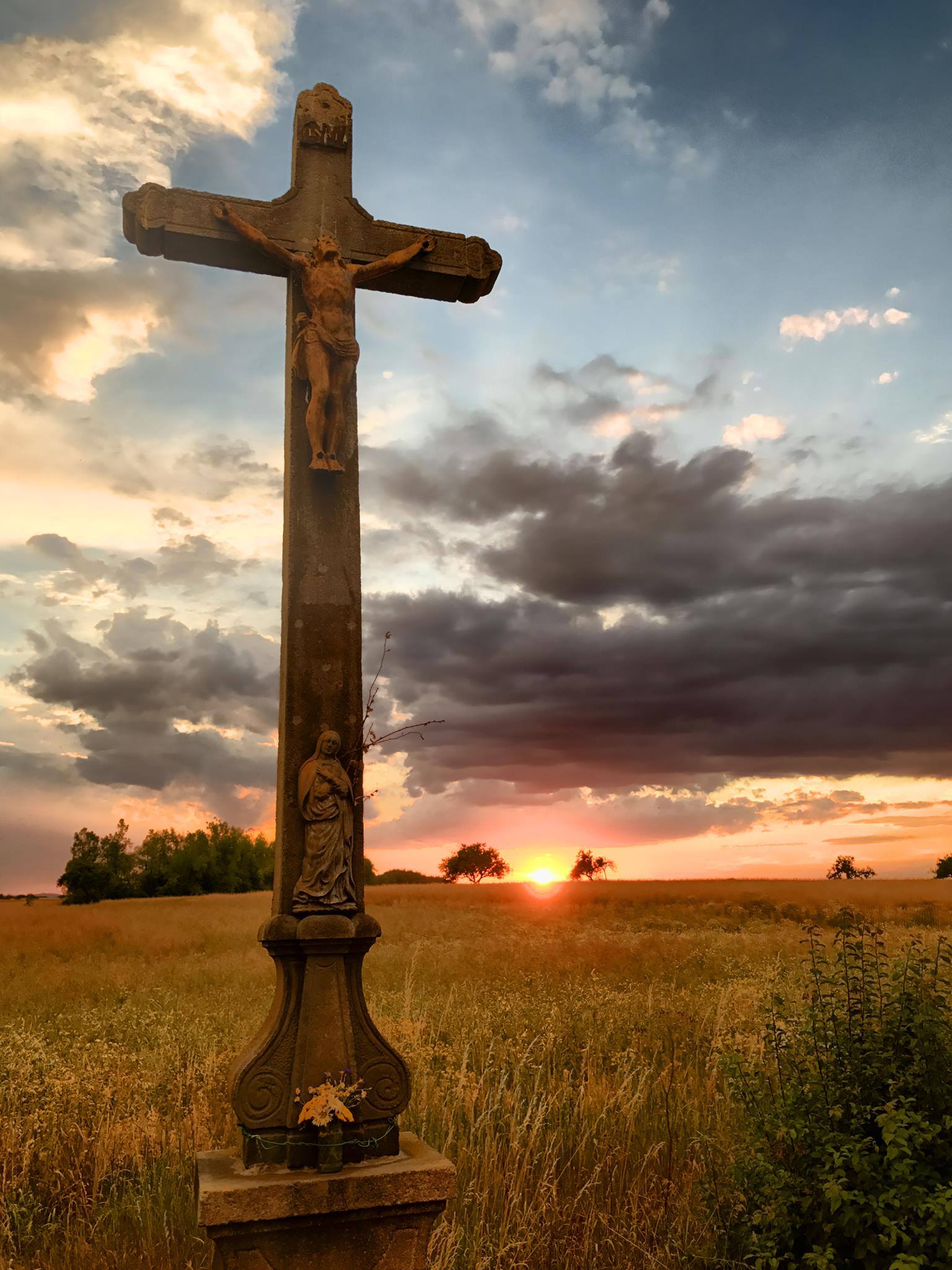 crucifix in field at sunset