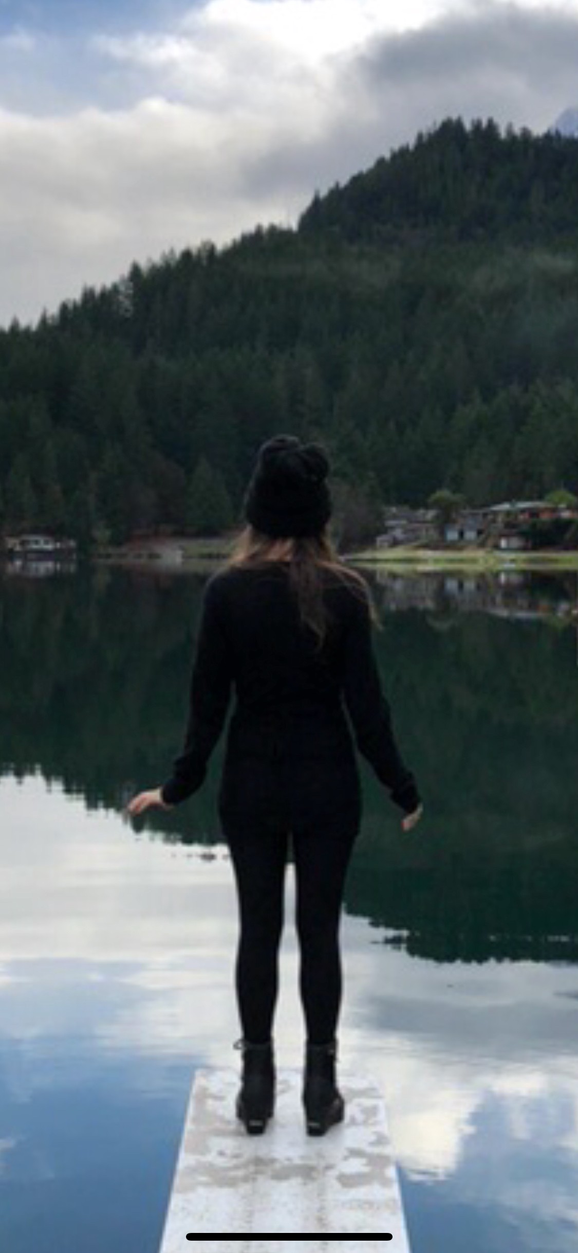 person standing on dock over lake