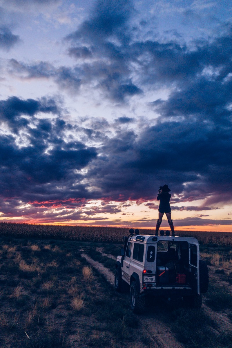 person standing on vehicle at sunset