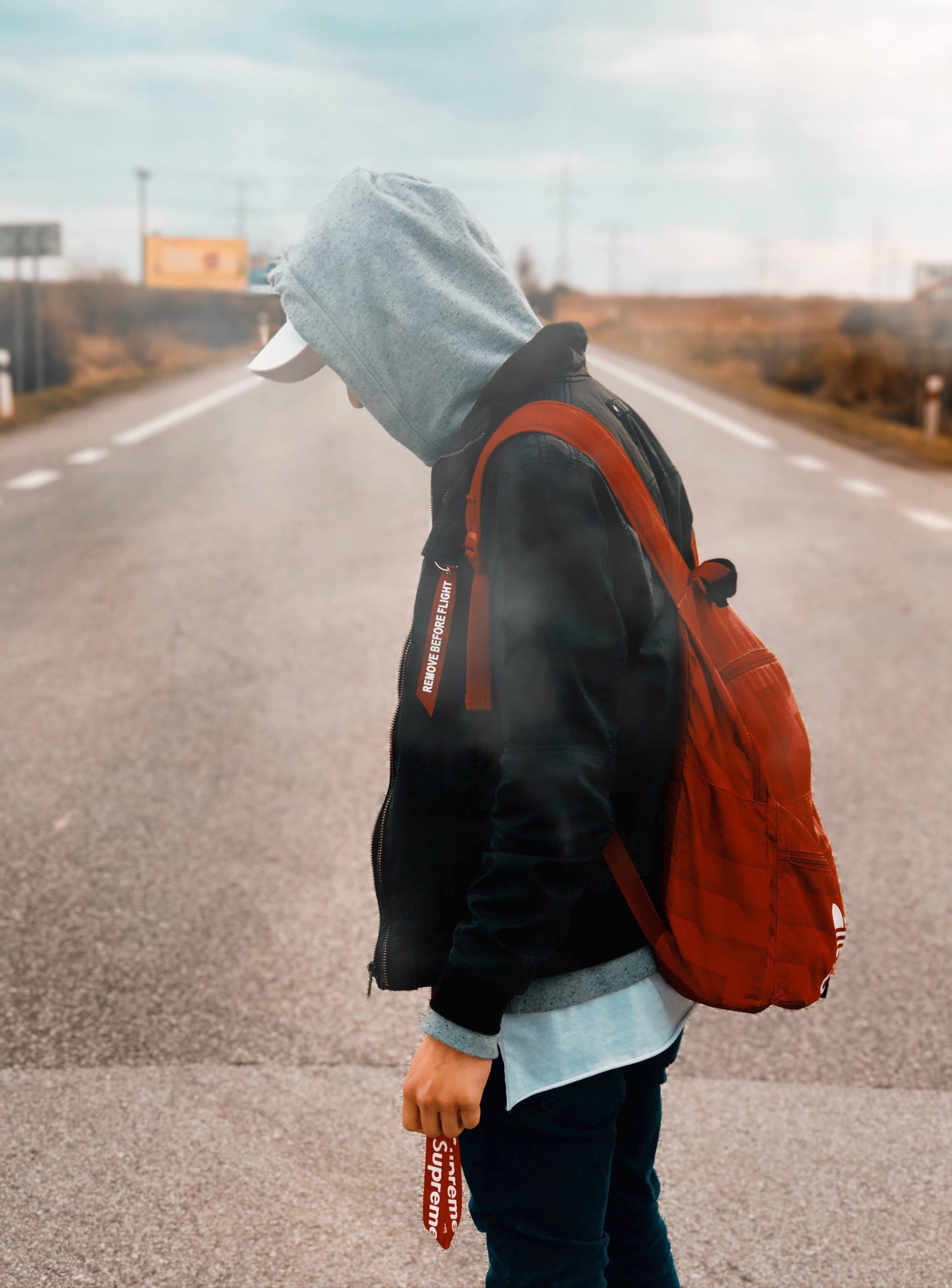 person with red backpack on road