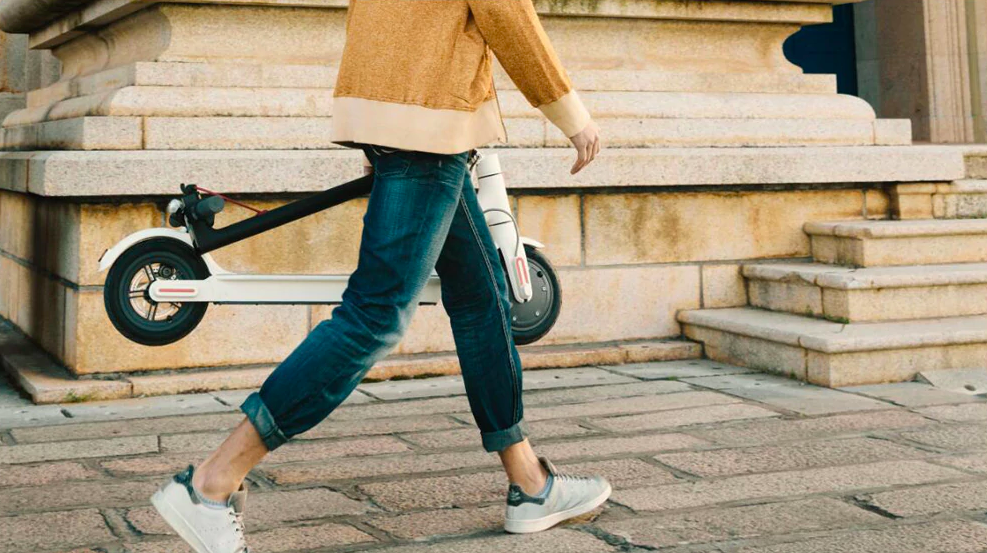 man carrying folded scooter