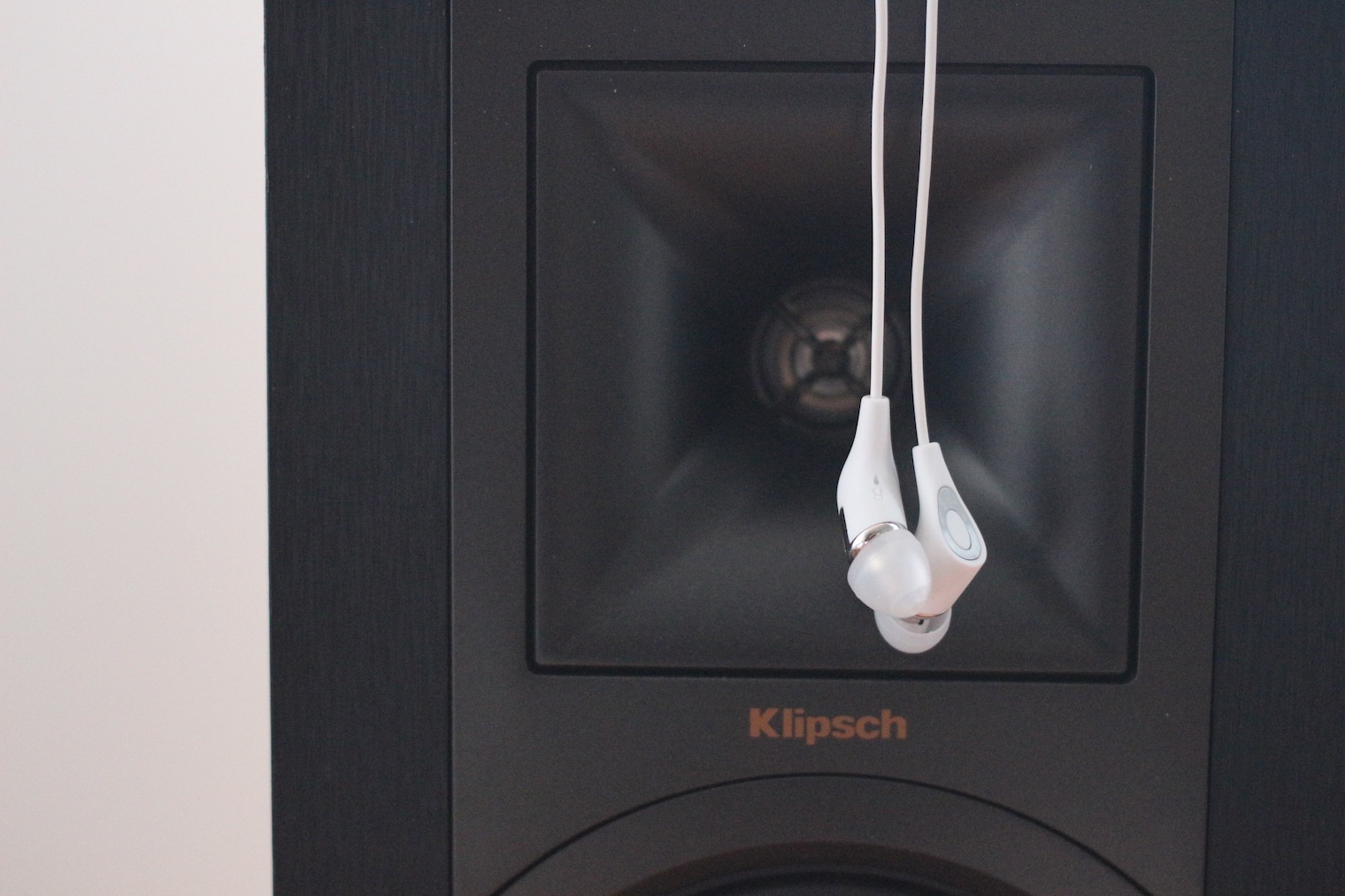 white earbuds hanging on speaker