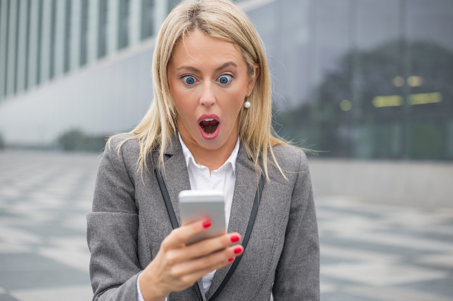 Surprised business woman looking at her smartphone. 