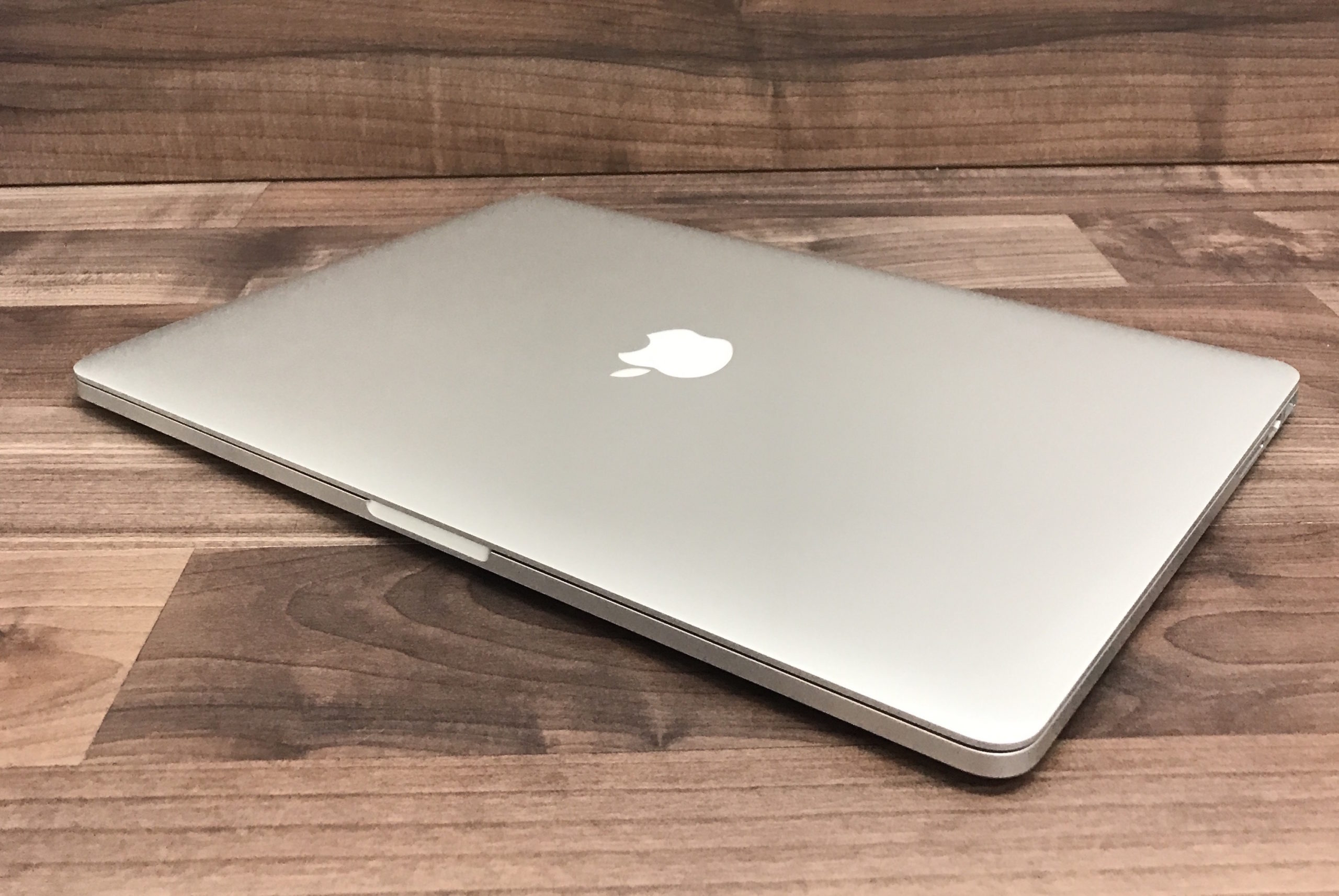 closed silver laptop angled wooden surface