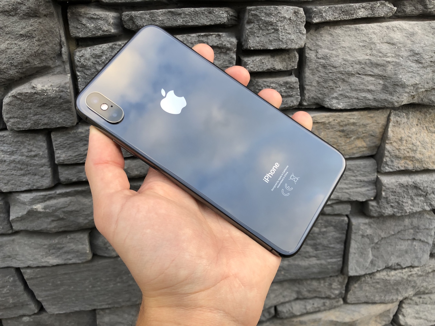 holding iphone back view stone wall