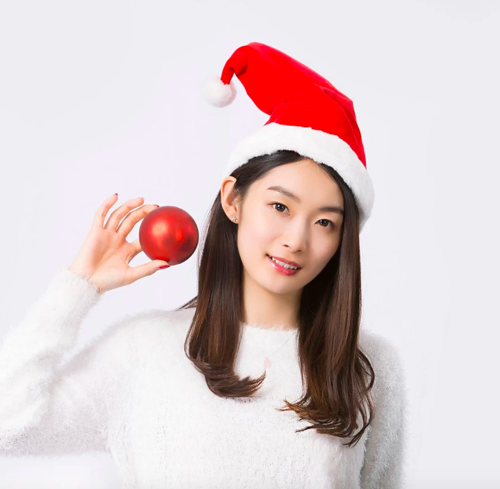 person wearing santa hat holding ornament