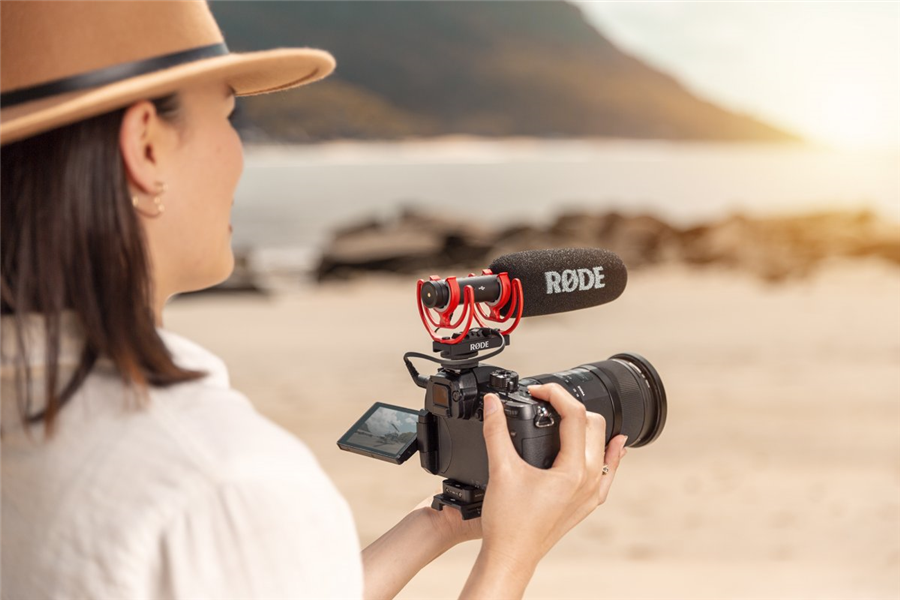 woman filming with camera on beach
