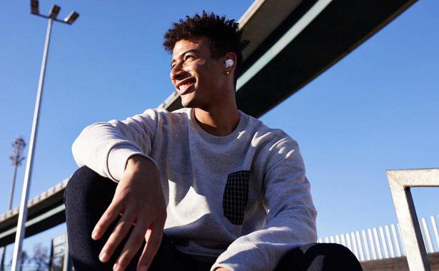 man smiling with earbuds outdoors