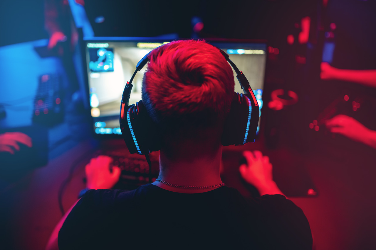 Professional gamer playing online games tournaments pc computer with headphones, Blurred red and blue background gaming adobestock