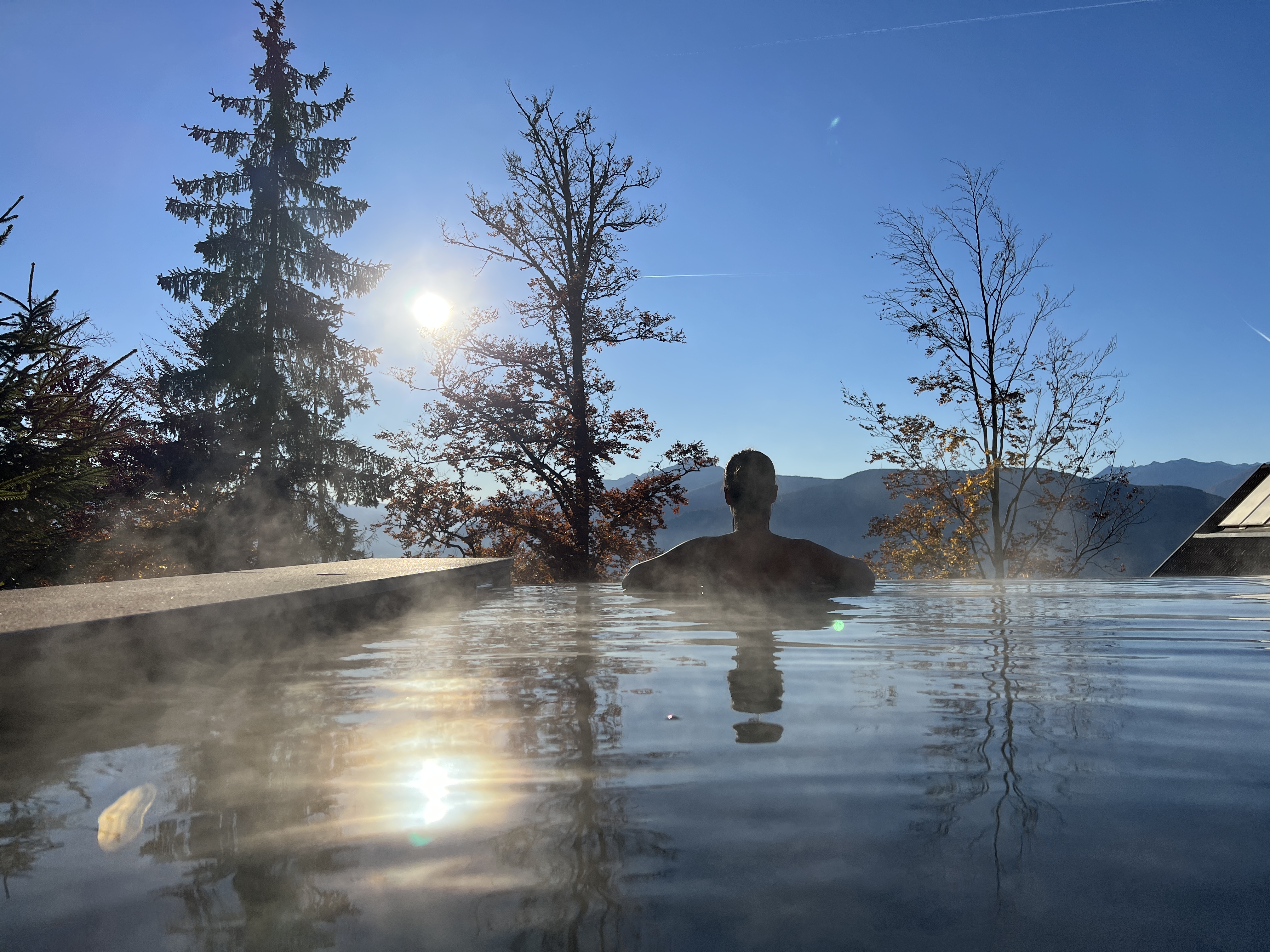 person in infinity pool with mountain view