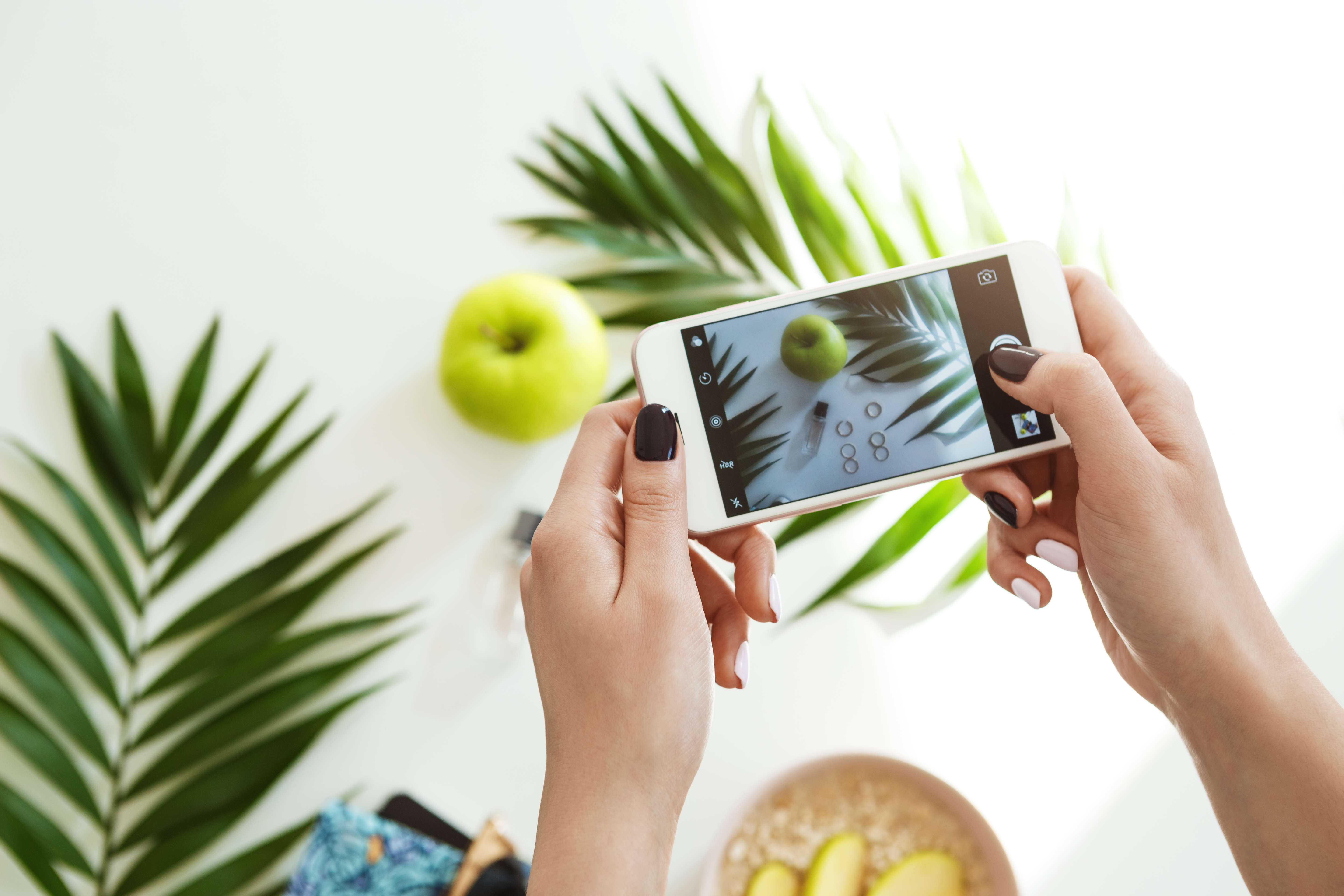 Woman hands with stylish nail polish holding phone taking pictures.