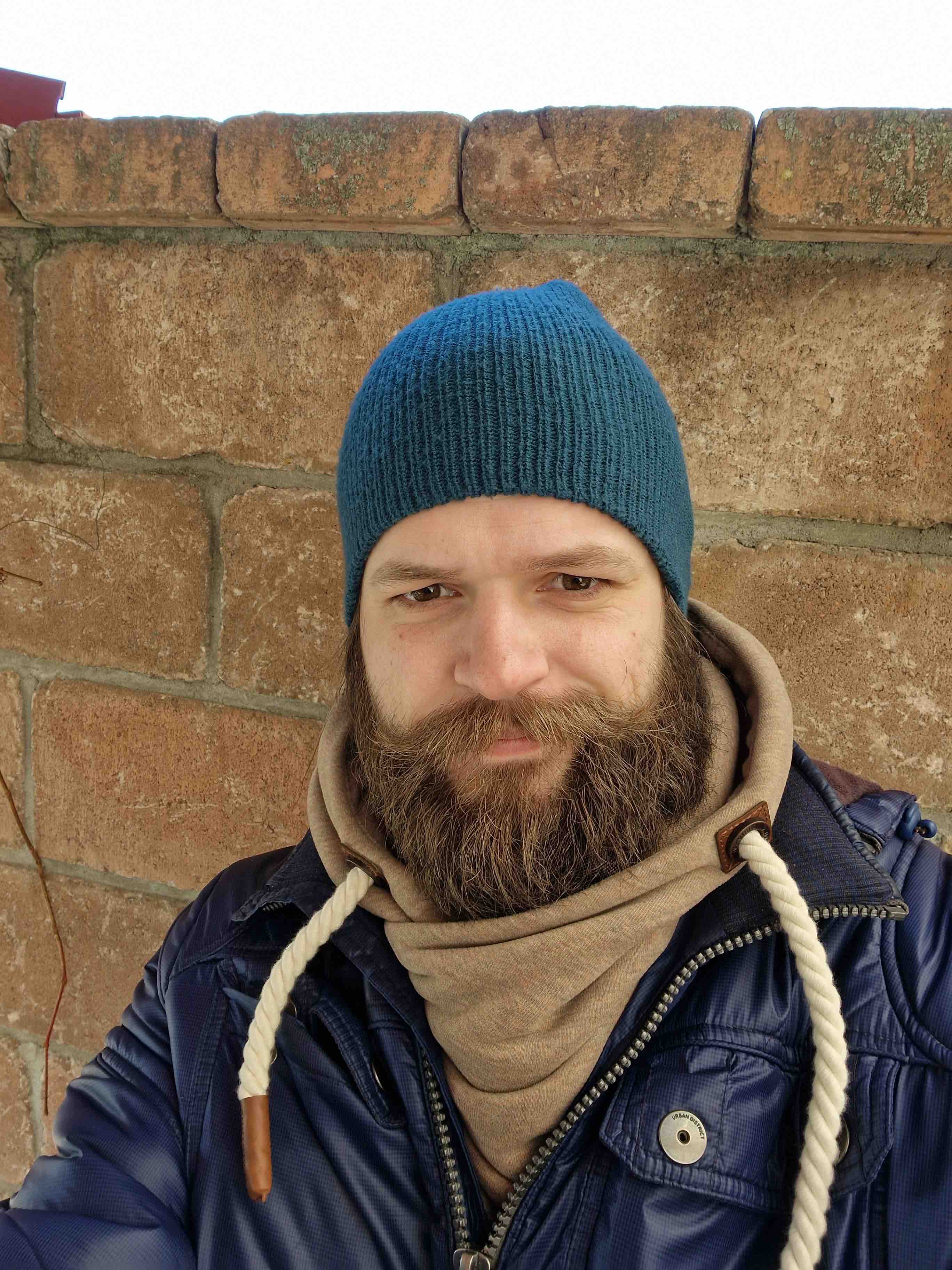 person blue beanie brick wall