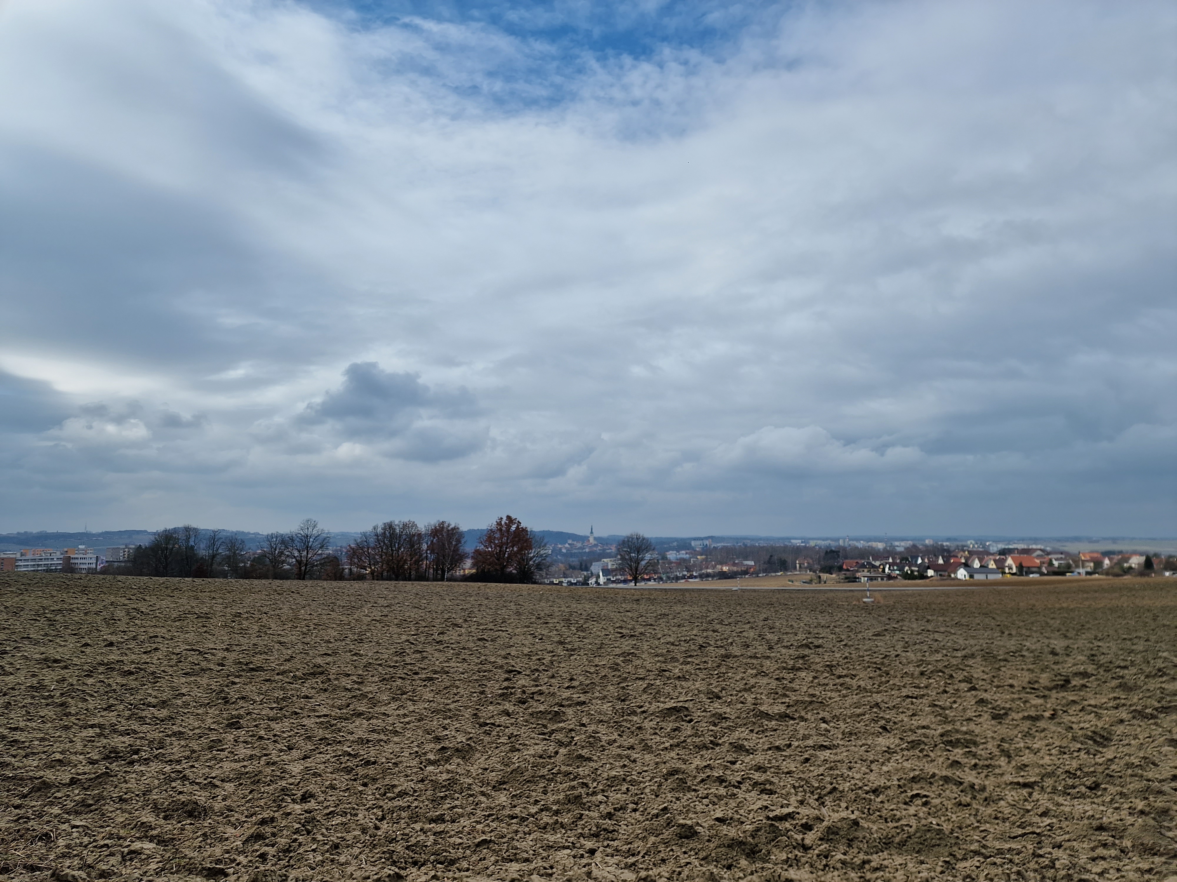 field with distant town and clouds
