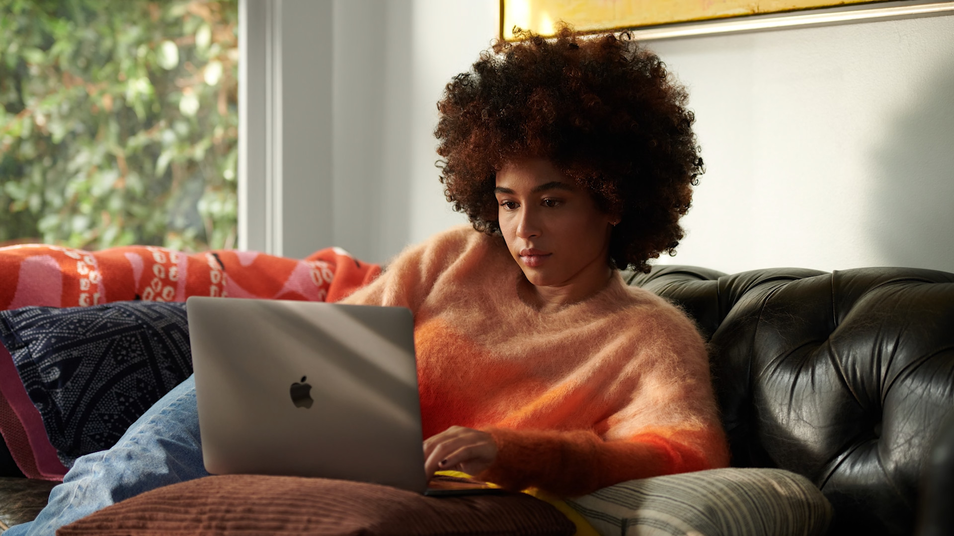 person using macbook on couch