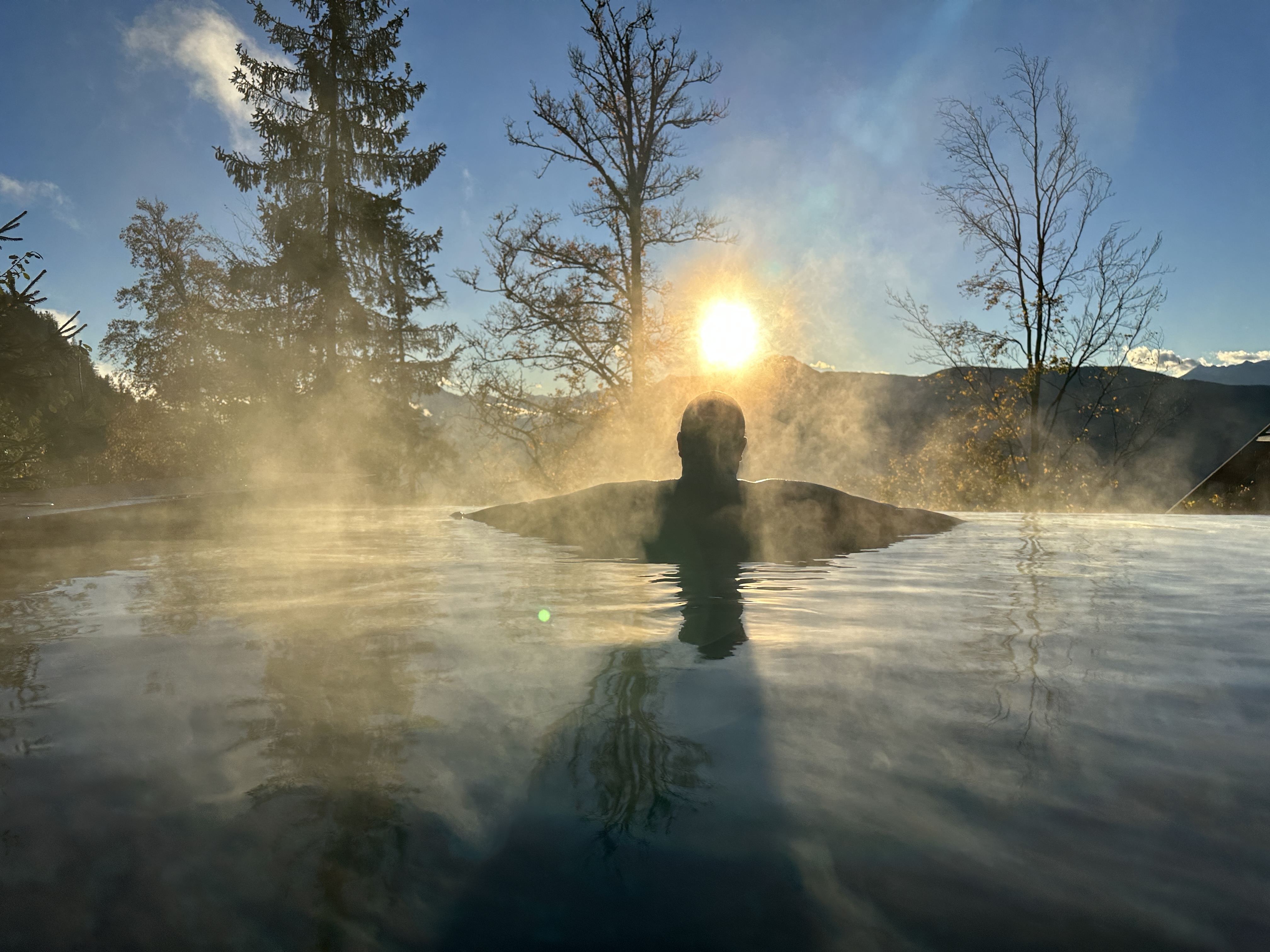 person in steaming pool at sunset