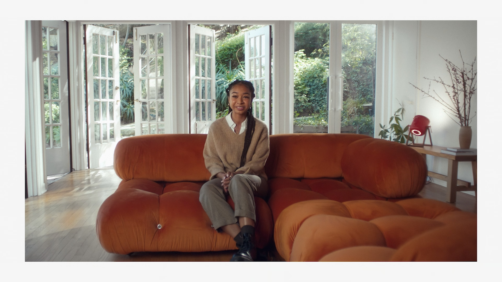 person on orange sofa in bright room