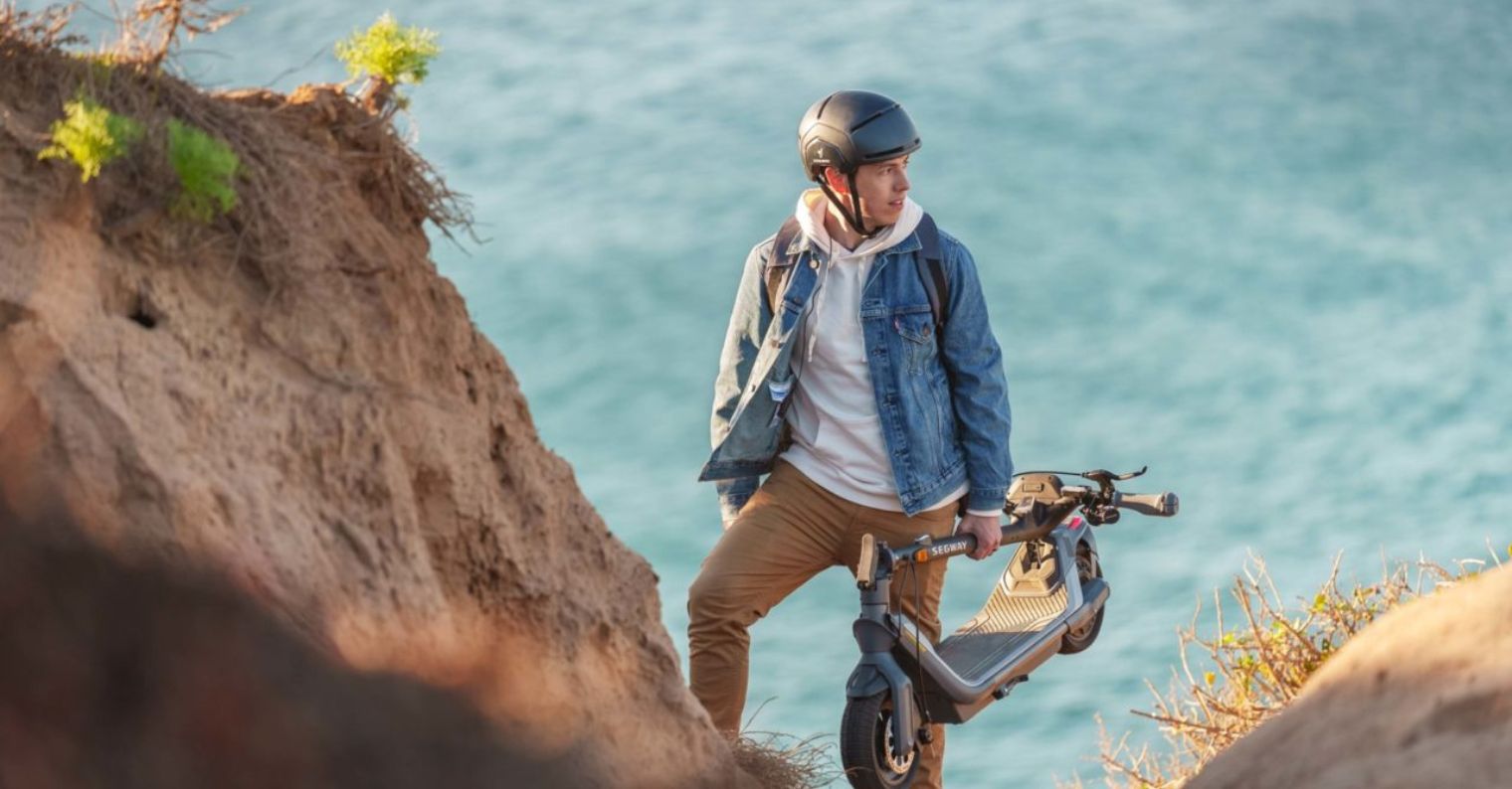 person carrying electric scooter on cliff