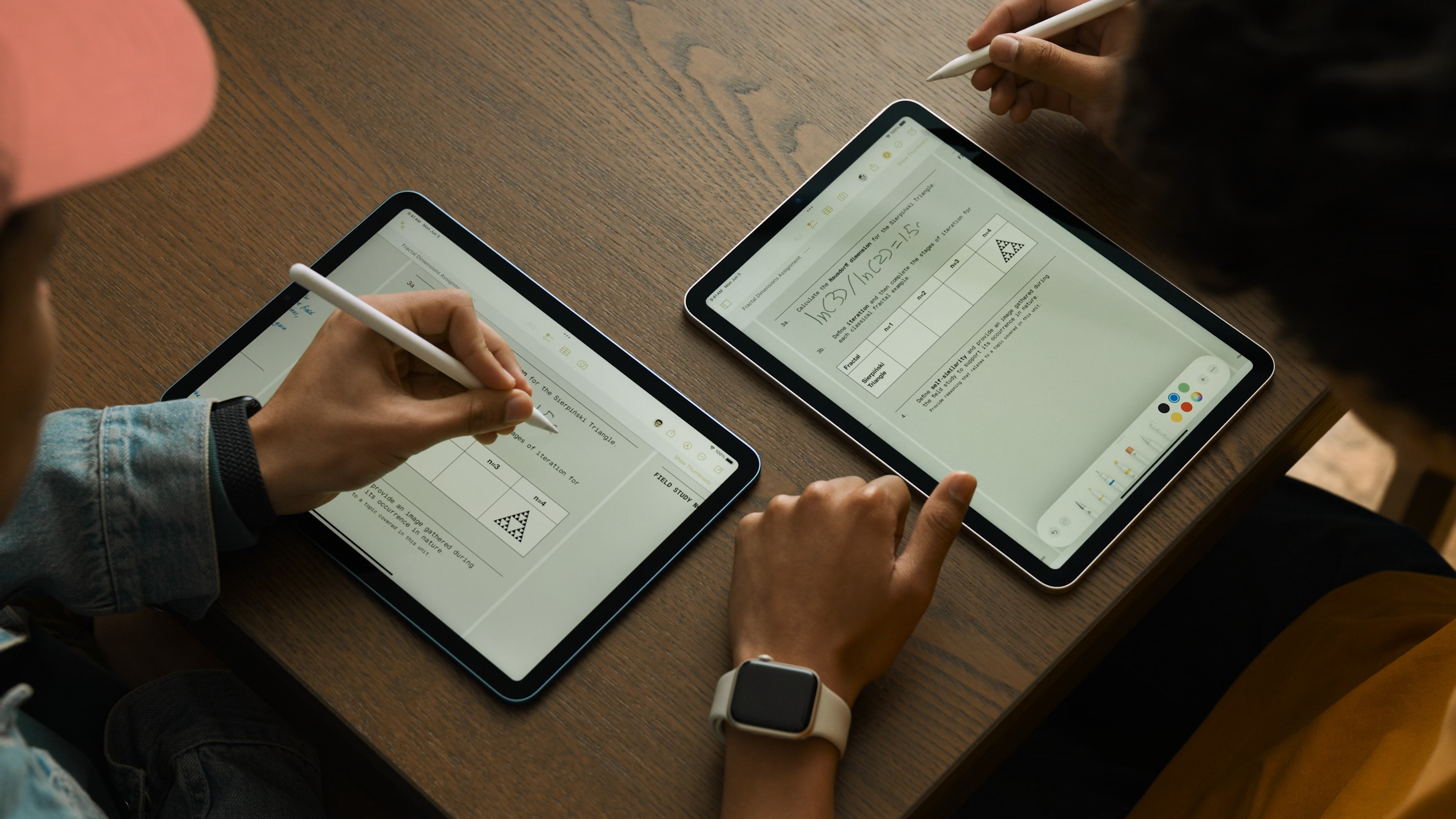 two people writing on tablets