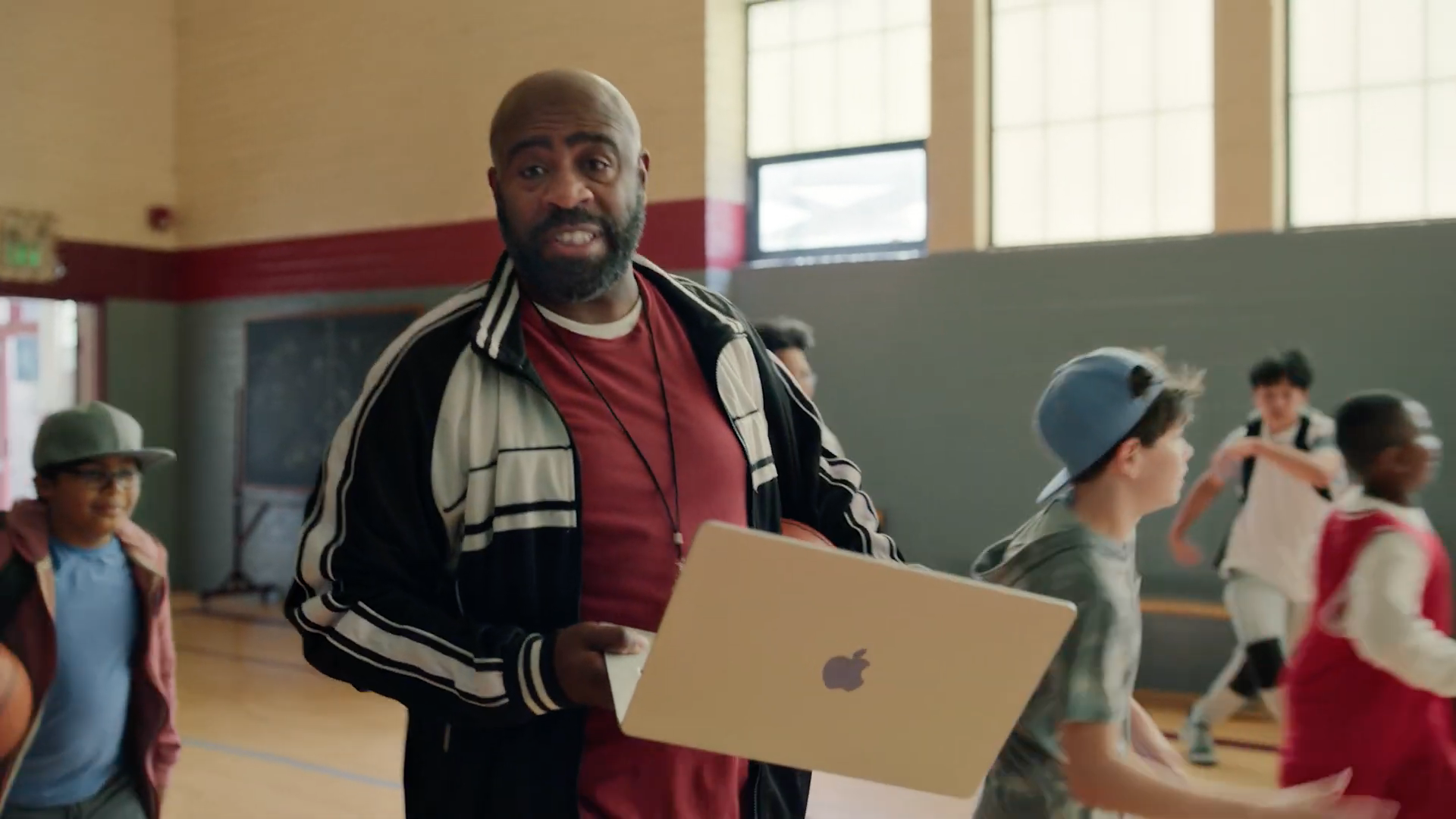 coach holding laptop in gym