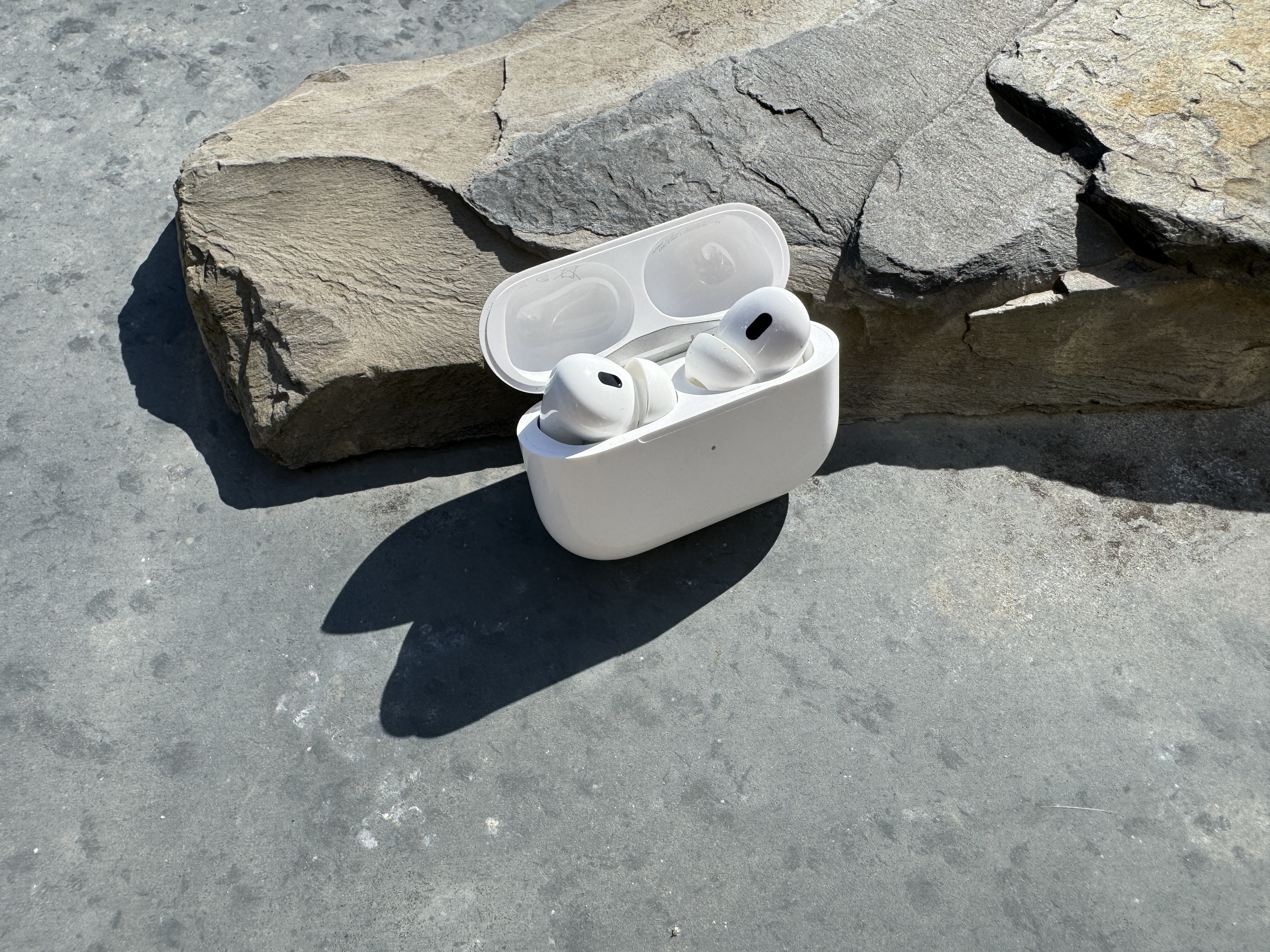 open wireless earbuds case on stone