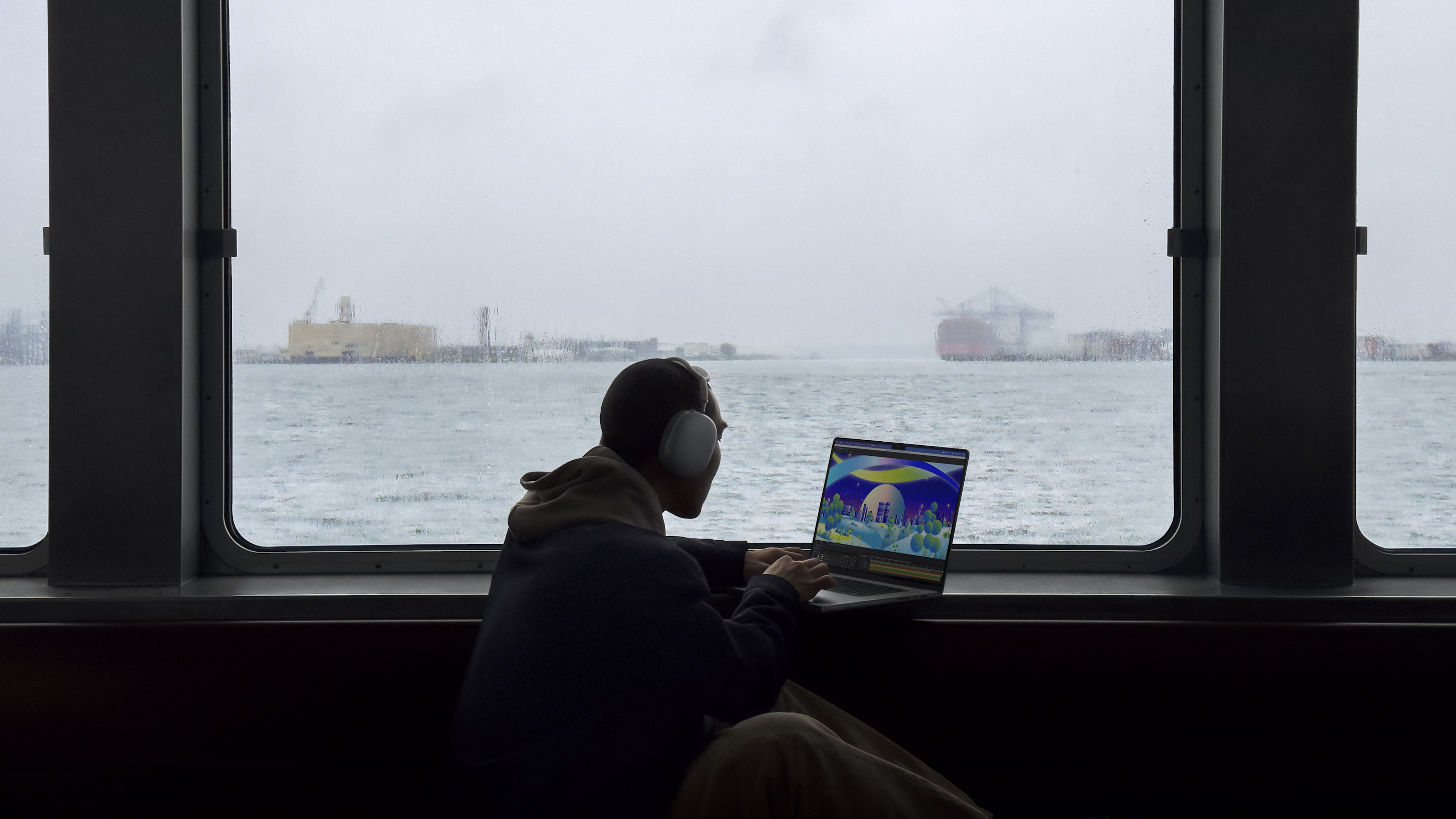 person on ferry using macbook