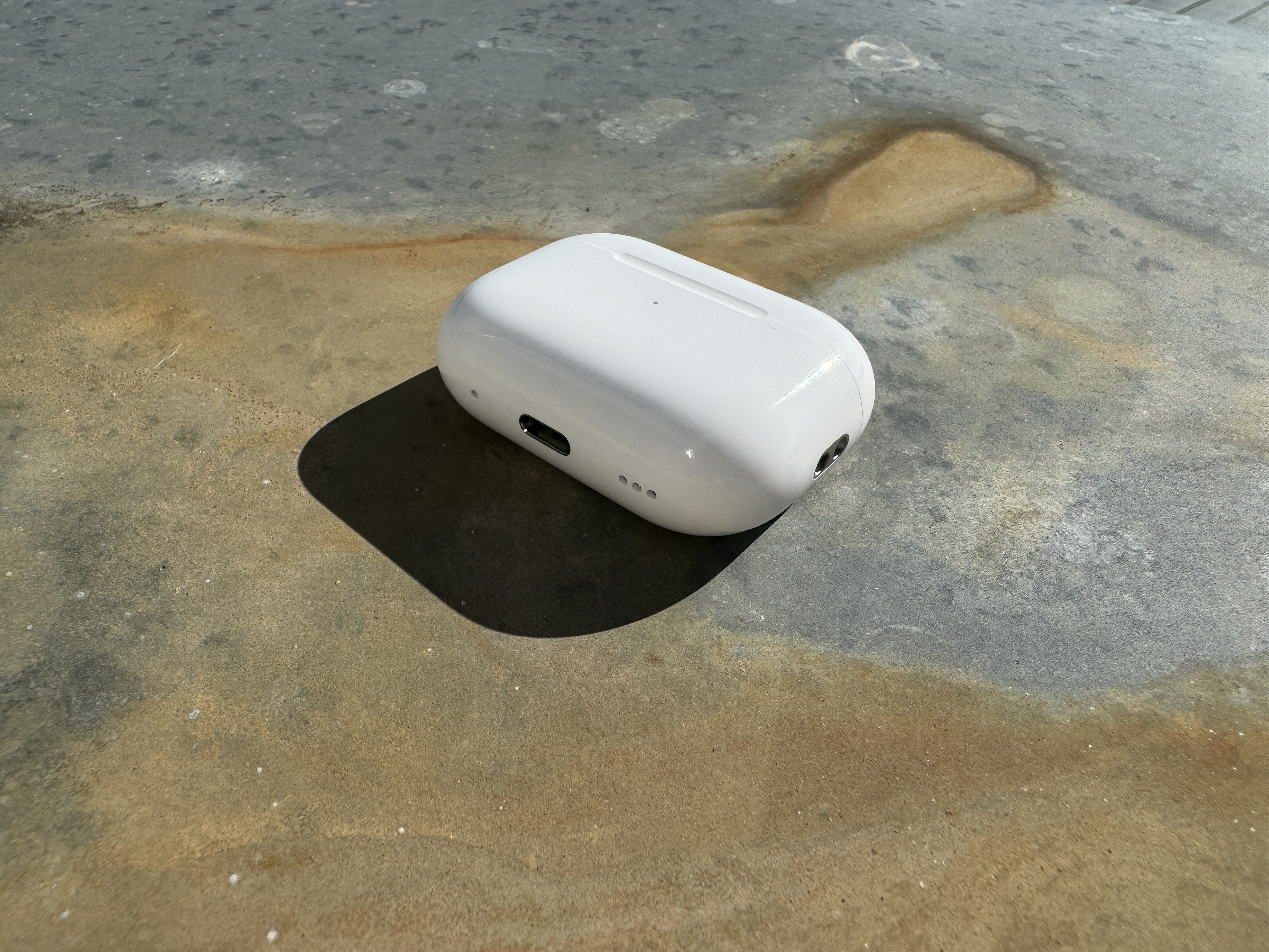 white wireless earbuds case on stone