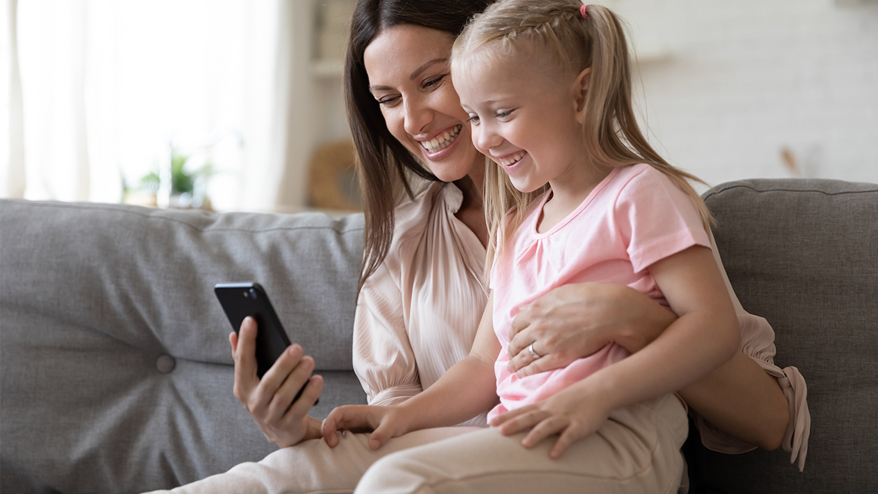 mother and daughter on sofa with phone