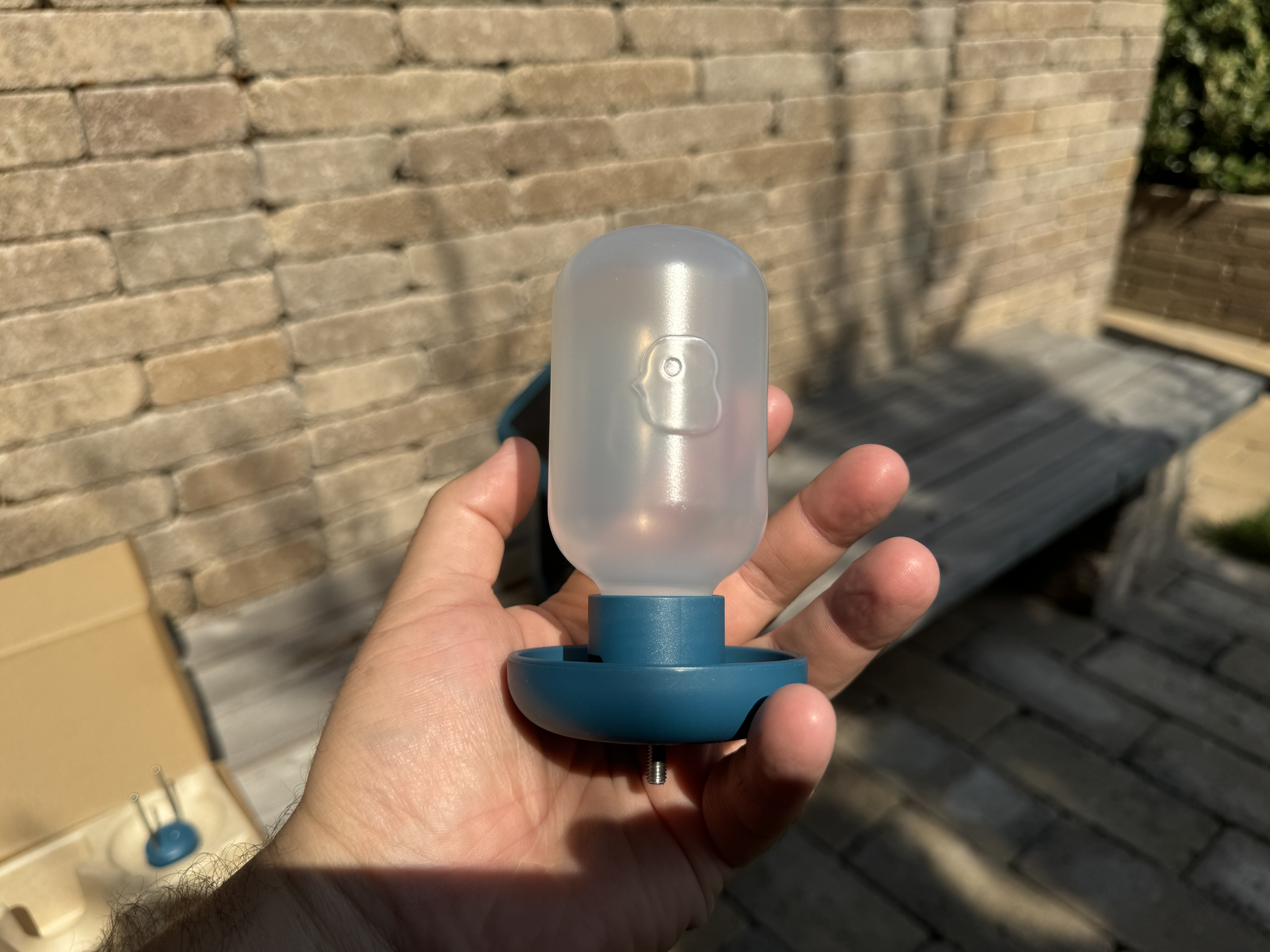 hand som håller vattenautomat för fågelholk