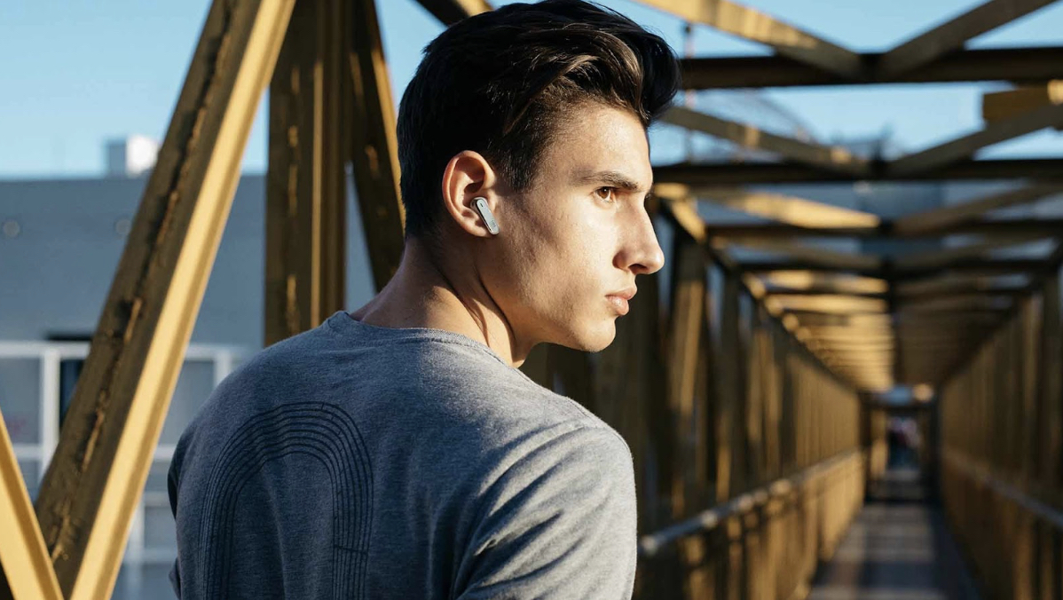 man wearing earbuds on bridge
