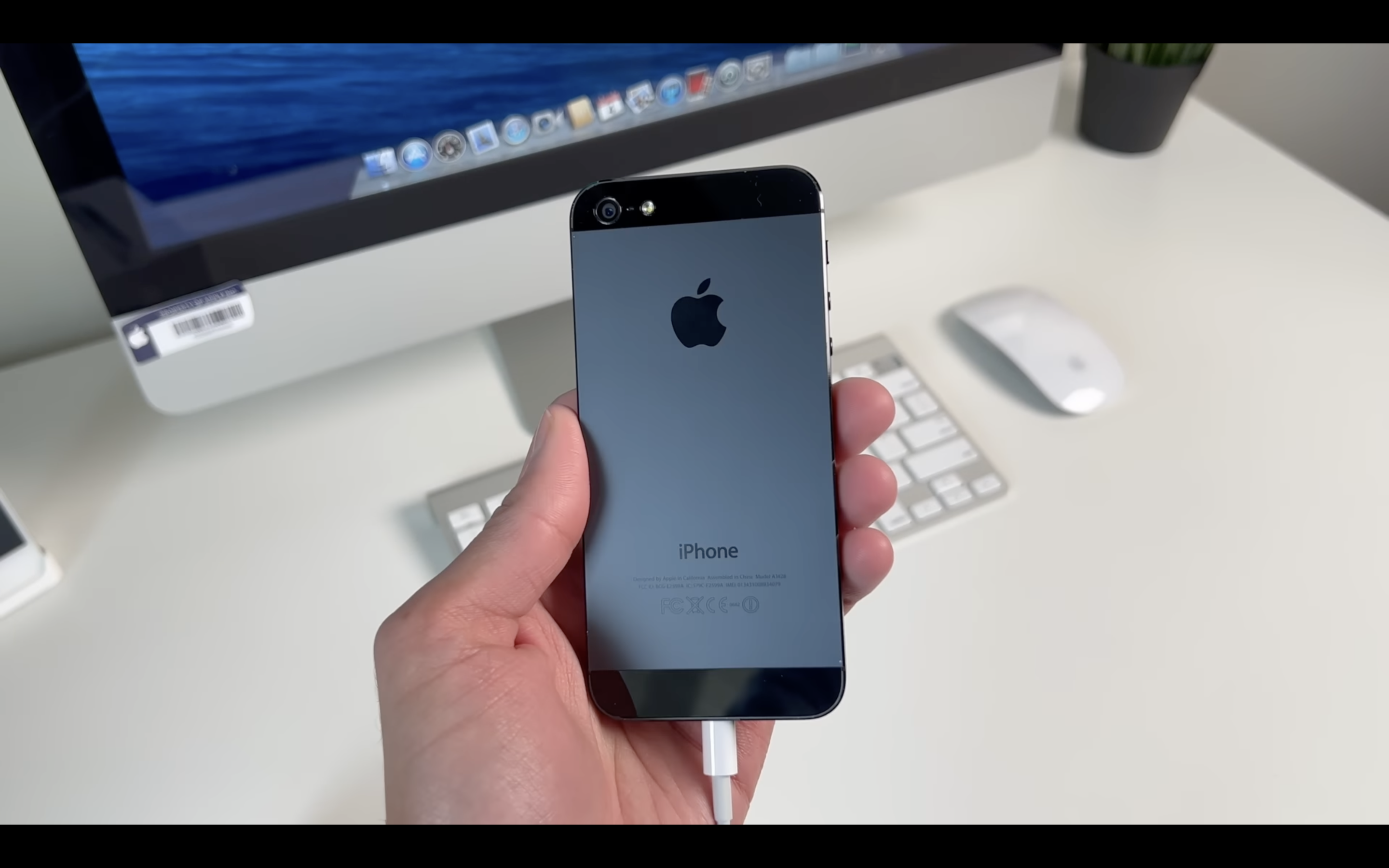 hand holding iphone in front of imac