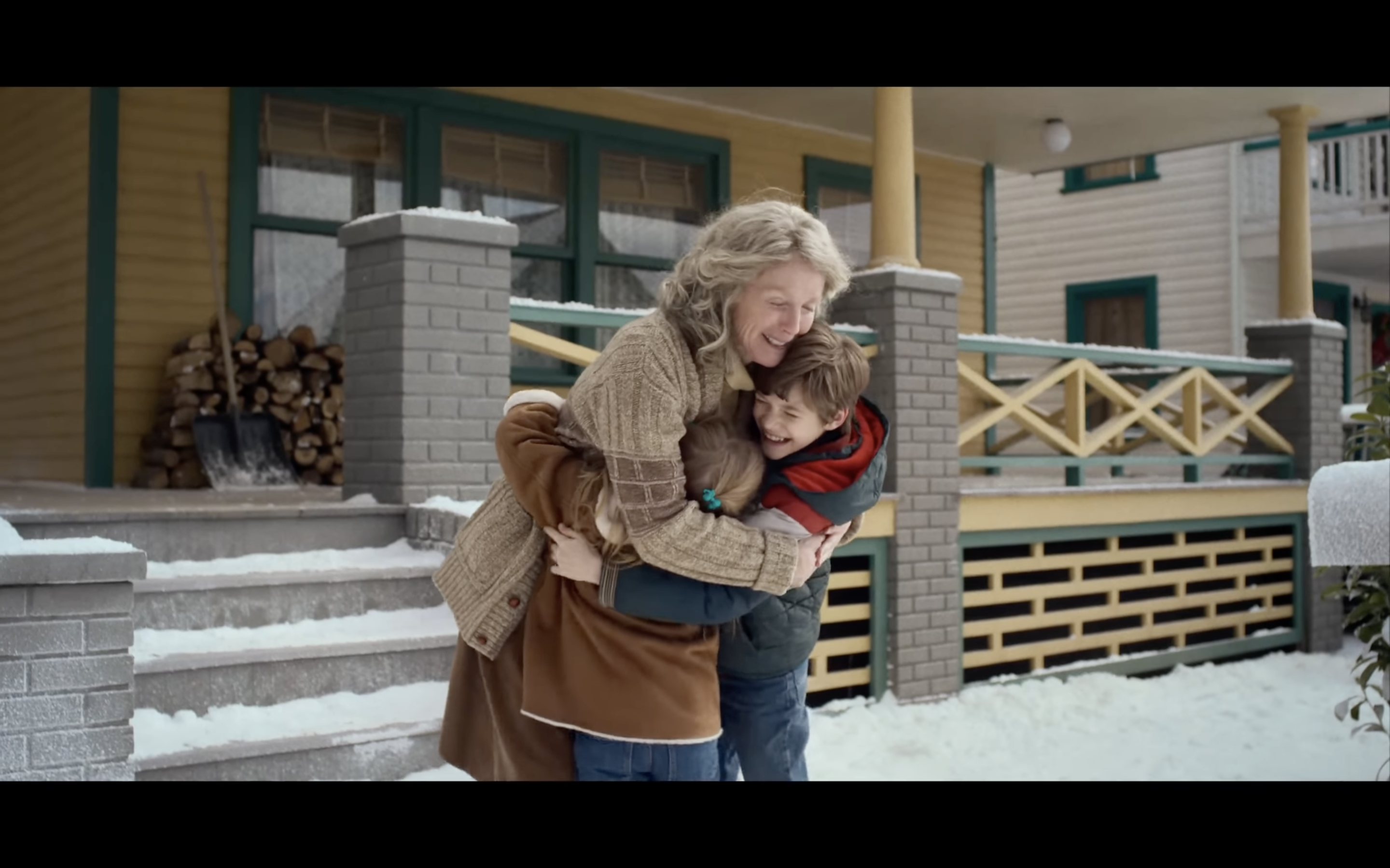 grandmother hugging children snowy porch