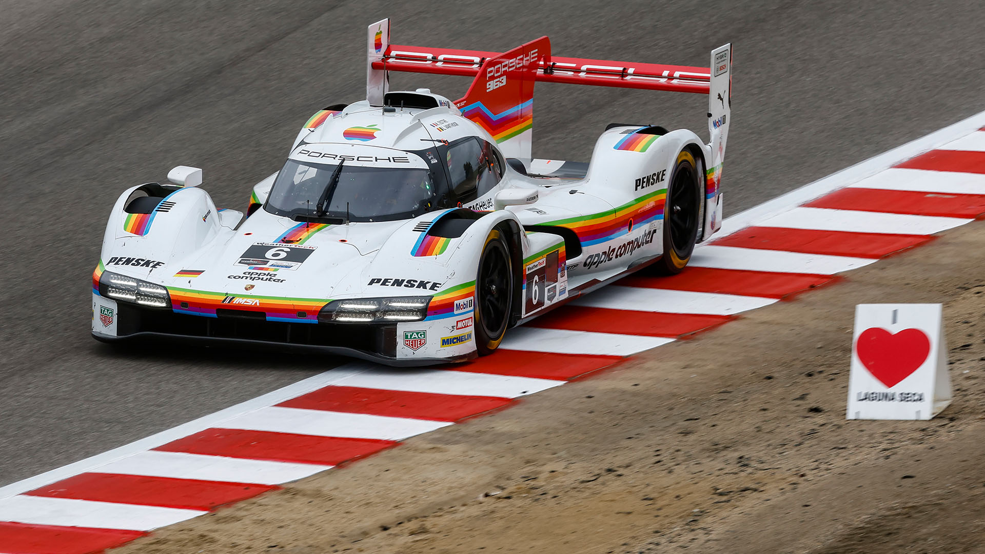 Front view of Porsche Penske Motorsport 963 racecar wearing Apple Computer livery competing on the track at the 2026 IMSA We